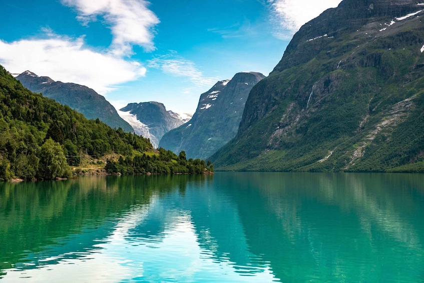 A tranquil lake surrounded by lush green mountains and a clear blue sky. 3