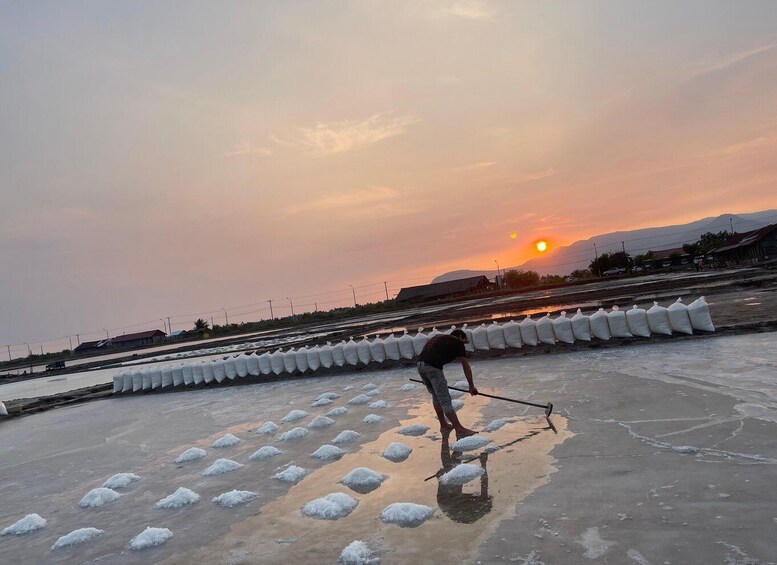 A person working on a salt flat during sunset. 1