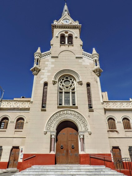 A church with a clock tower, arched windows, and a large wooden door. 4