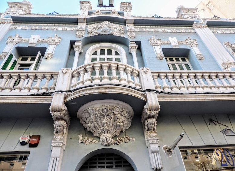 A building with ornate architectural details, including a balcony with balustrades and a decorative pediment. 1