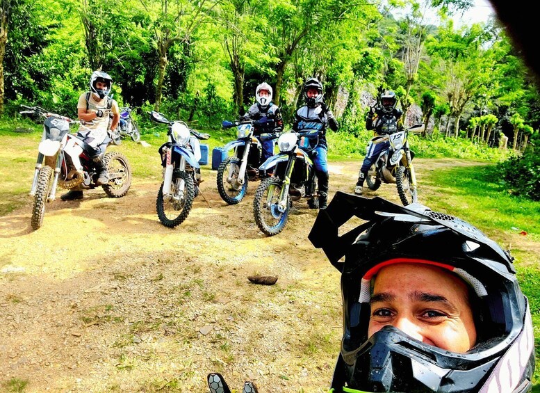 A group of motorcyclists on a dirt road surrounded by greenery. 5