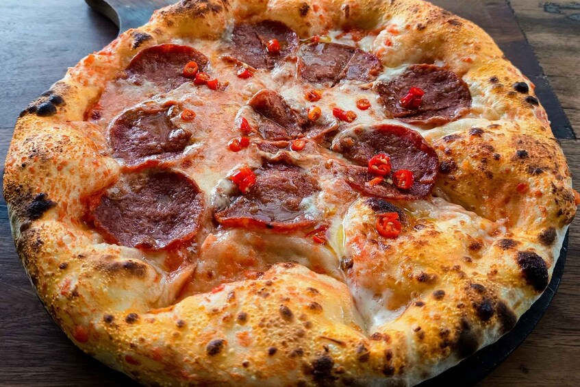 A pizza with pepperoni and cheese on a wooden surface. 2
