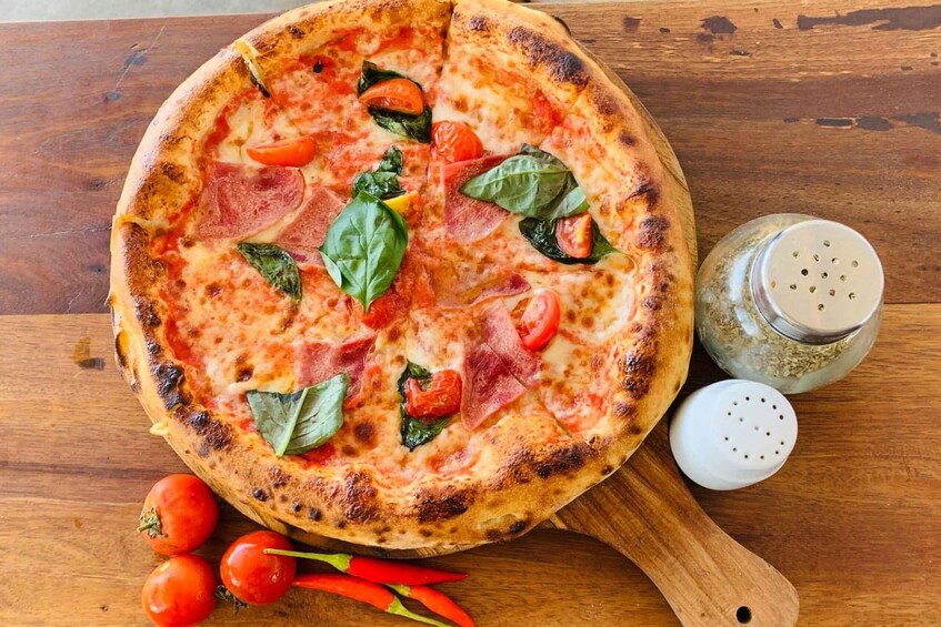 A pizza with tomato, basil, and pepperoni toppings on a wooden board. 5