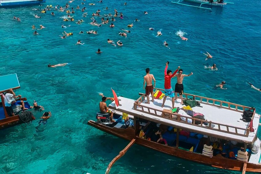 A boat with people swimming in the water. 1