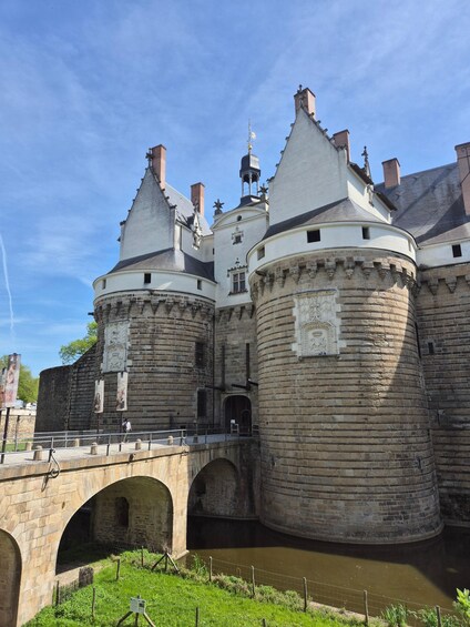 A historic castle with multiple towers, a moat, and a stone bridge. 1