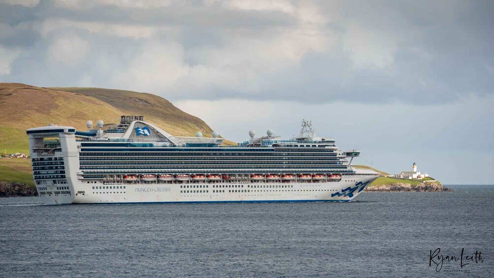 A large cruise ship named 'Caribbean Princess' sailing near a coastal area with a lighthouse in the background. 3