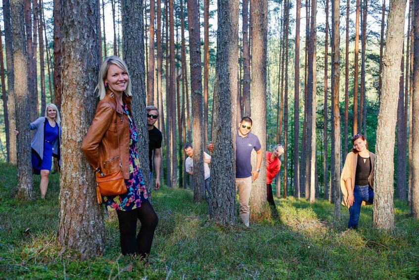 A group of people in a forest with tall trees and grassy ground. 5
