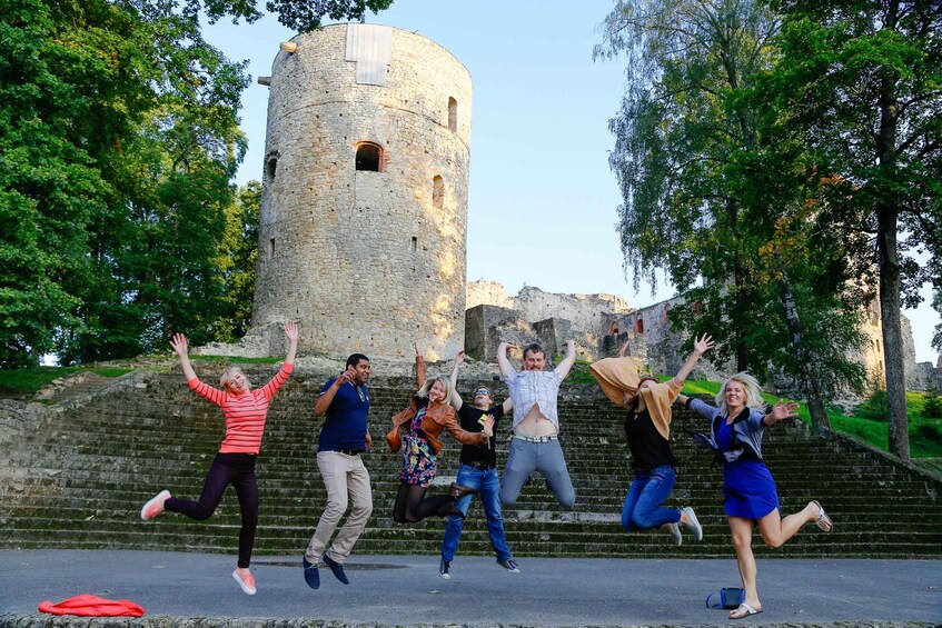 A group of people jumping in front of a historic stone tower. 3