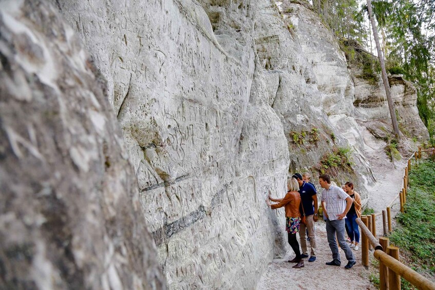 A group of people standing on a rocky trail with a wooden railing on the right. 2