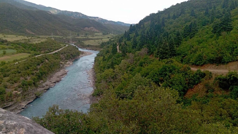 A river winding through a valley with dense forested hills. 5