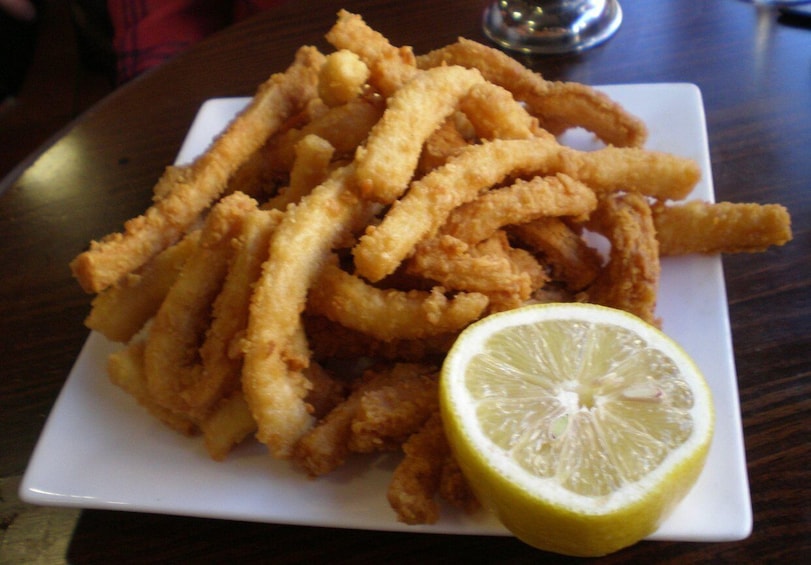 A plate of fried calamari with lemon wedges. 5