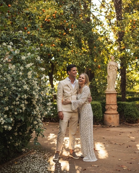 A couple embracing in a garden with orange trees and a statue. 3