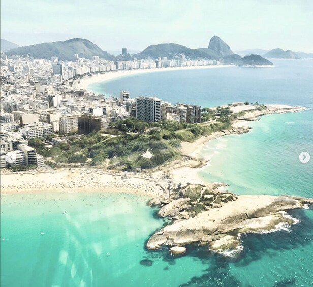 A coastal city with a beach, buildings, and mountains in the background. 3