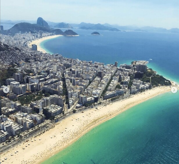 A coastal city with a long sandy beach, dense urban area, and a prominent mountain in the background. 5