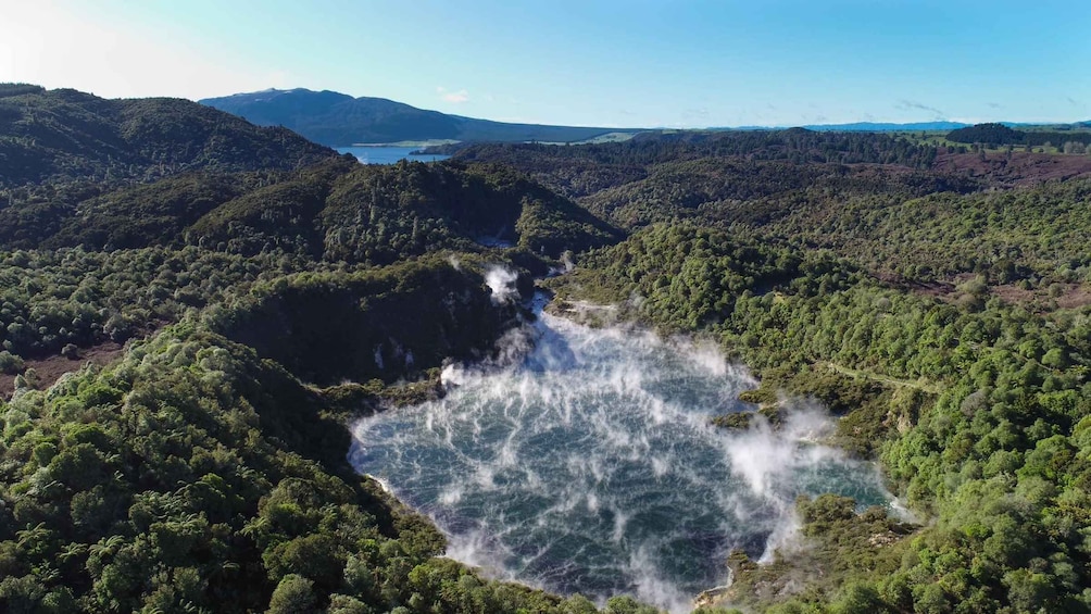 A waterfall cascading into a forested valley with mountains in the background. 5