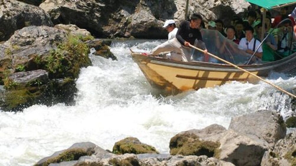 A group of people in a small boat navigating a fast-flowing river with rocky banks. 1