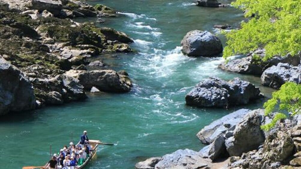 A river with rocks and a boat carrying people. 2