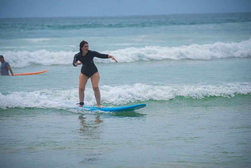 A person surfing on a blue board in the ocean. 3