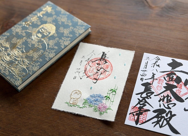 A book with a blue cover and two pieces of paper with Japanese calligraphy. 5