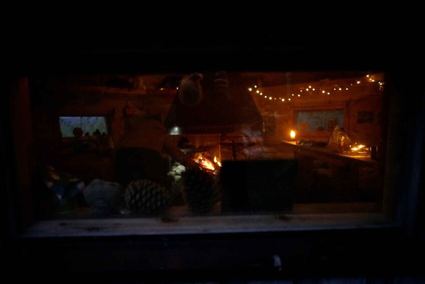 A dimly lit interior with a fireplace, wooden furniture, and string lights. 4