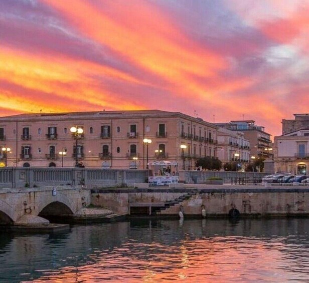 A sunset over a city with a bridge and buildings reflecting on the water. 1