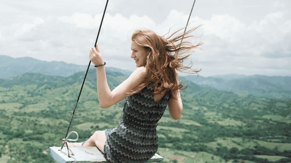A person on a swing with a mountainous landscape in the background. 2
