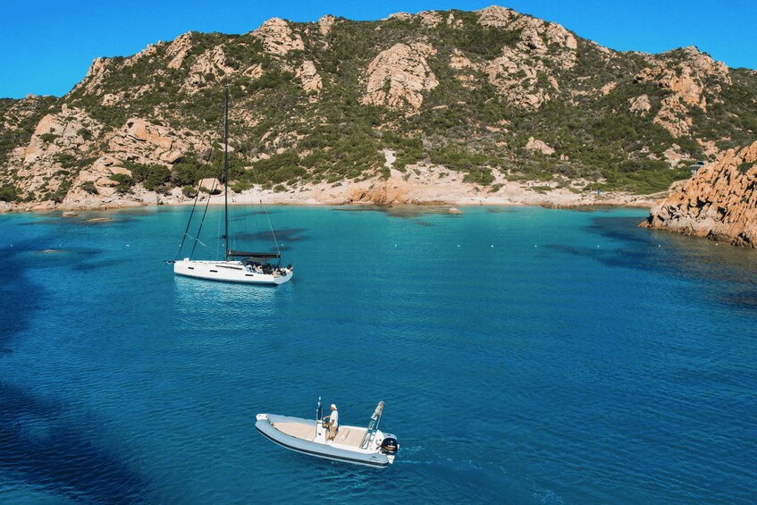 A coastal landscape with two boats on calm waters, surrounded by rocky cliffs and sparse vegetation. 2