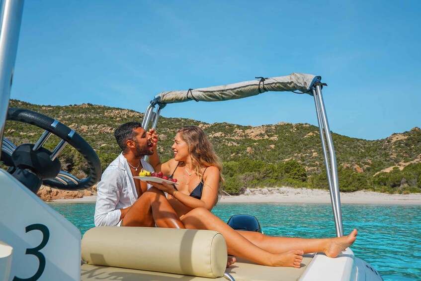 A couple on a boat with a clear view of the coastline and hills in the background. 5