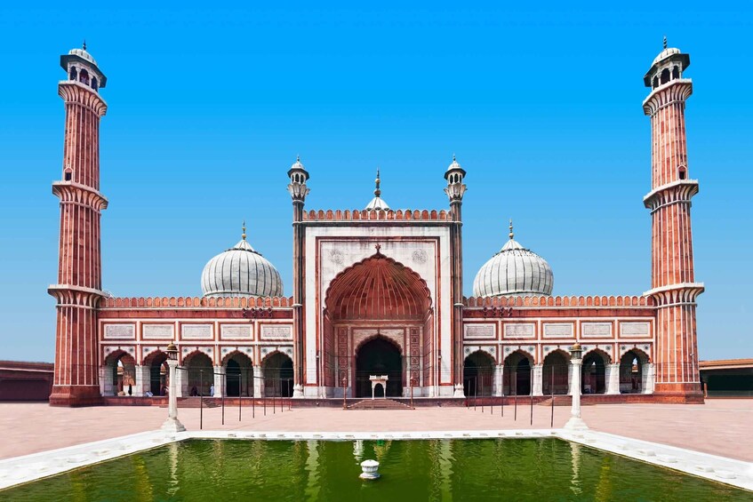 A large, ornate building with two tall minarets, a central dome, and a surrounding courtyard with a water feature. 2