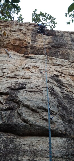 A person rappelling down a rocky cliff with a rope. 2