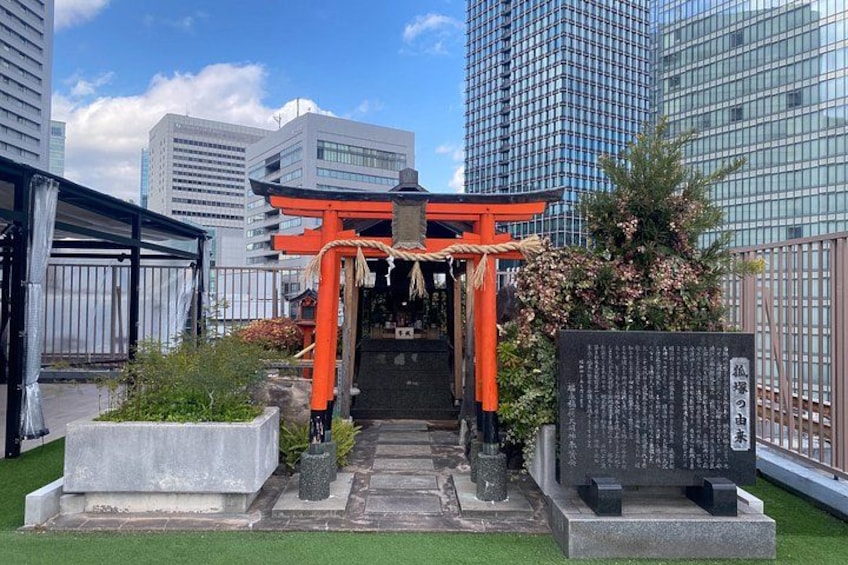 A traditional Japanese torii gate in an urban setting with modern buildings in the background. 2