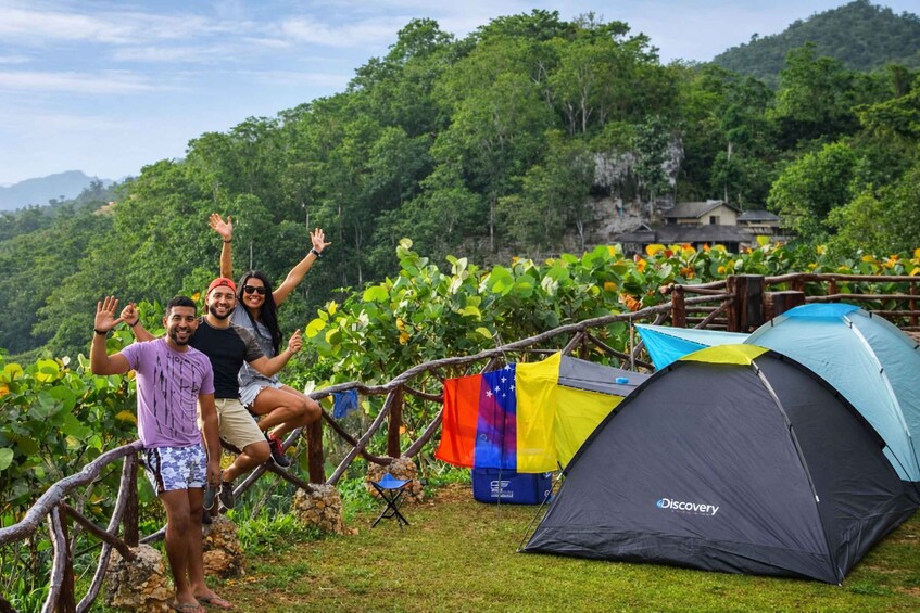 A group of people on a grassy hill with a tent labeled 'Discovery' and a flag. 1