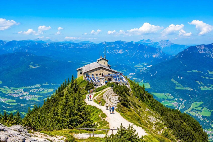 A mountain lodge with a path leading to it, surrounded by forest and alpine scenery. 5