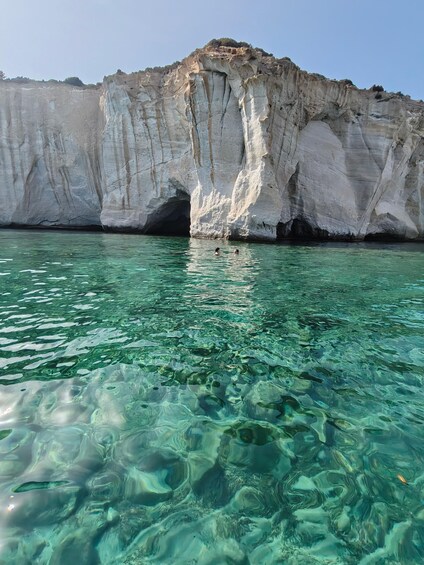 A clear blue sea with rocky cliffs and a cave entrance. 3