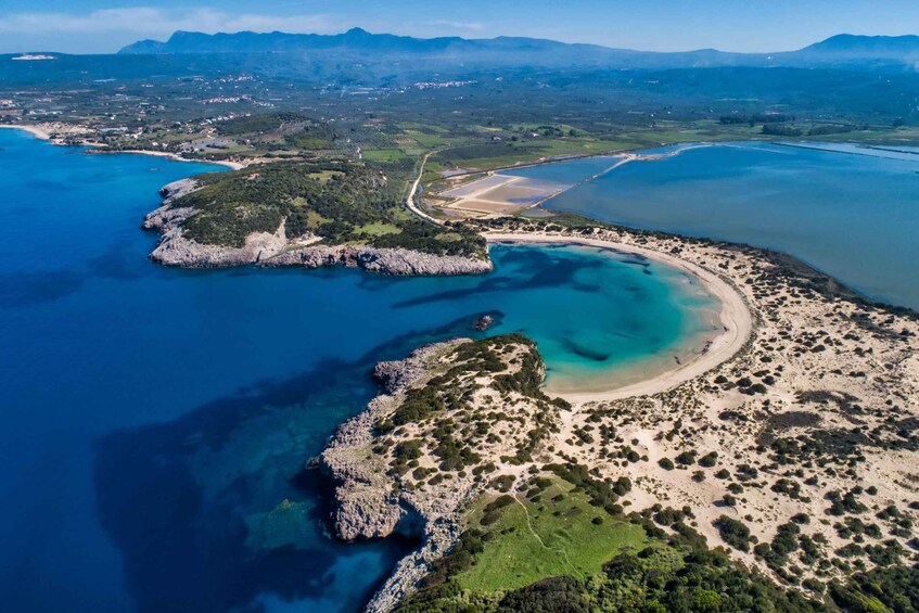 An aerial view of a coastal landscape with a bay, sandy beaches, and a small island with rocky outcrops. 1