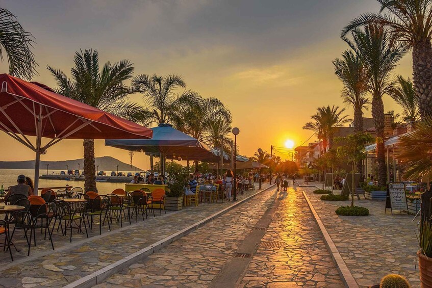 A sunset at a seaside café with outdoor seating and palm trees. 3