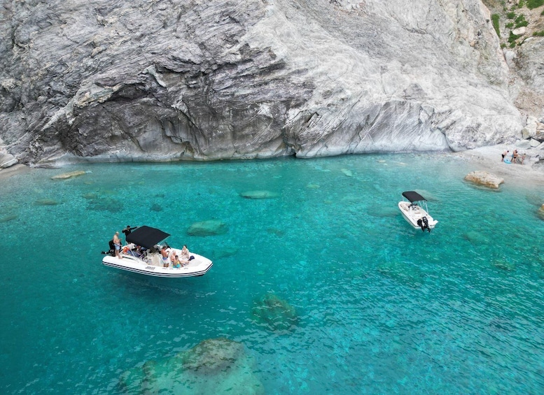 A boat with passengers in clear turquoise waters near a rocky coastline. 1