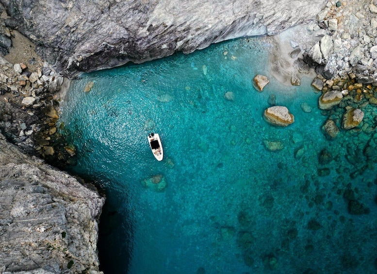 A boat in a turquoise bay surrounded by rocky cliffs. 4