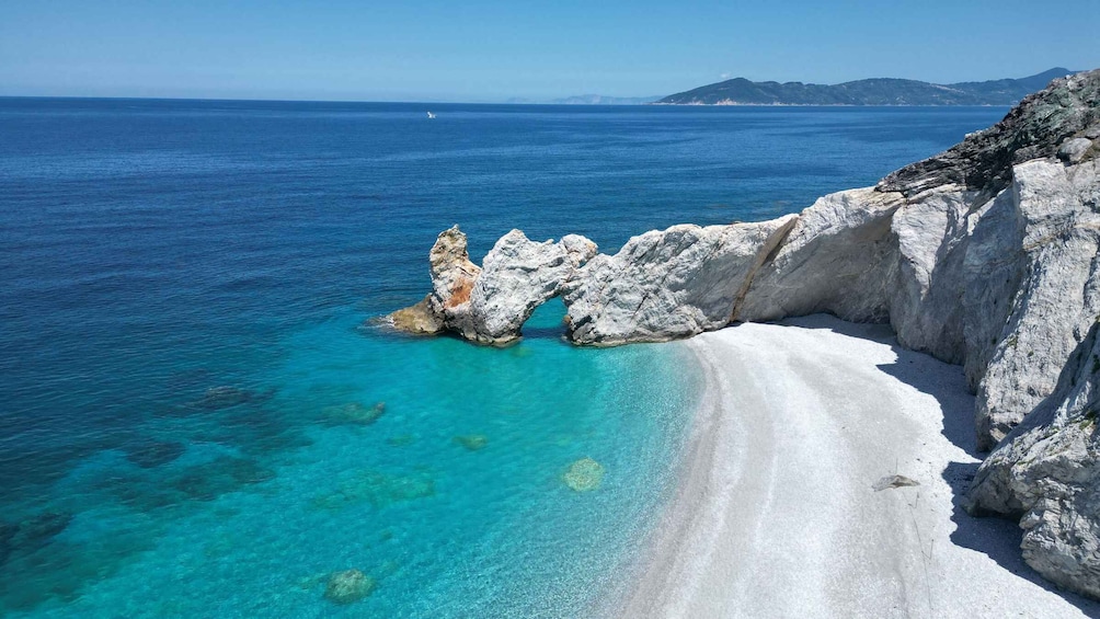 A beach with clear turquoise waters, white sand, and rocky formations. 3