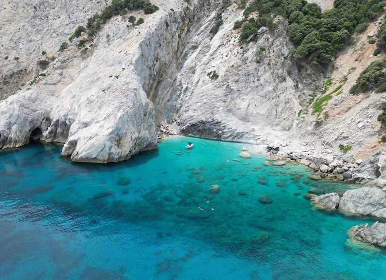 A turquoise sea with rocky cliffs and a boat. 2