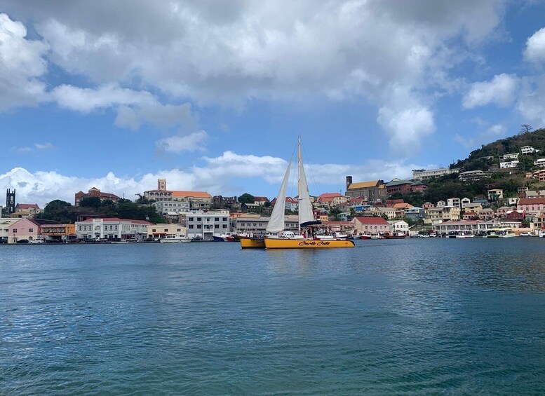 A coastal town with a prominent white sailboat, buildings, and a hill in the background. 5