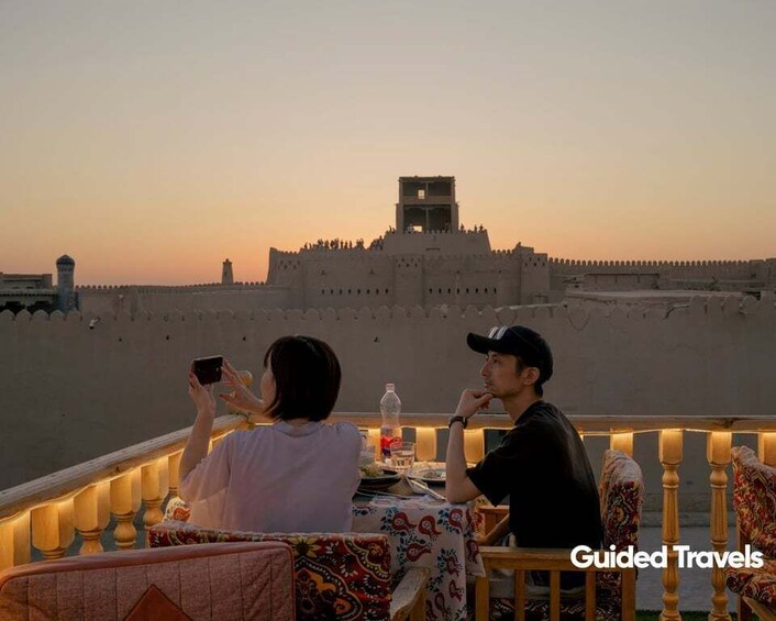 A couple dining at a table with a view of a historic fort. 1