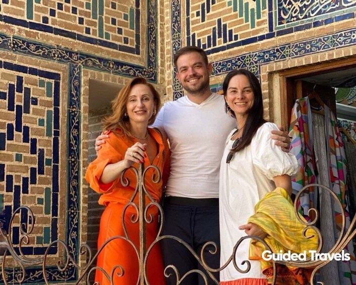 A group of people standing in front of a building with intricate tile work. 3