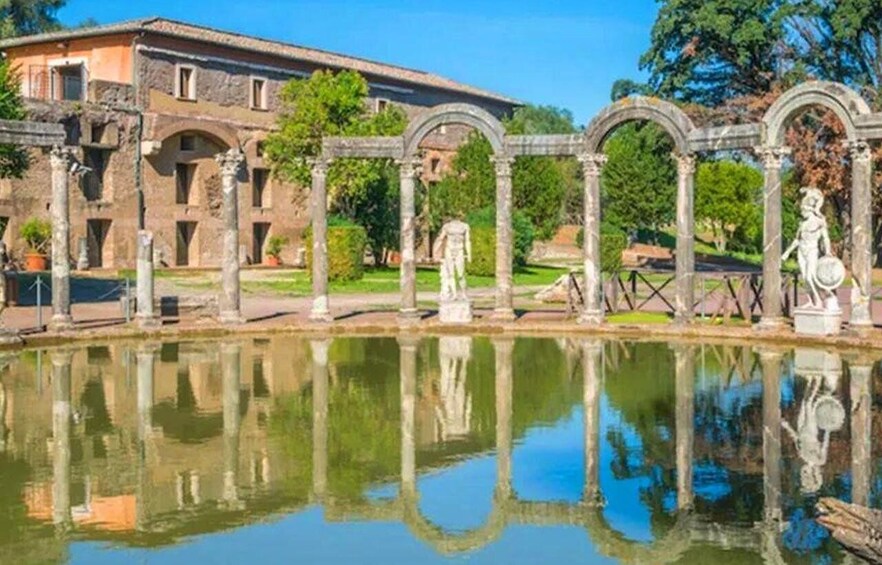 Ancient ruins with columns and statues, a reflecting pool, and a building in the background. 3