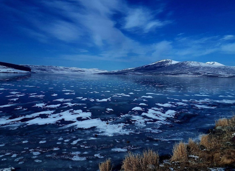 A frozen lake with snow-covered mountains in the background. 1