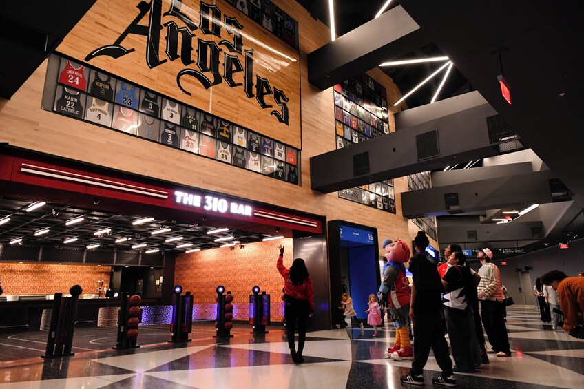 A sports-themed indoor area with a large wooden sign reading 'Los Angeles,' a bar named 'THE 310 BAR,' and a basketball court with a checkered floor. 5