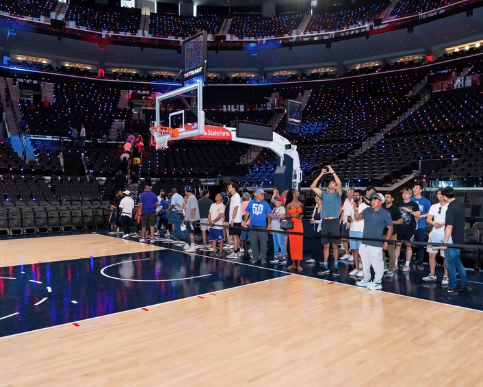 An indoor basketball court with spectators, a basketball hoop, and a scoreboard. 1