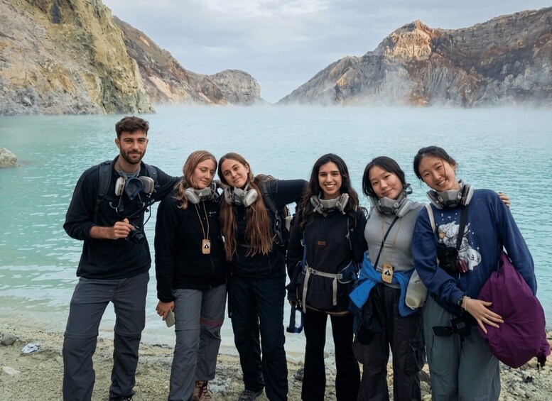 A group of people with headsets standing by a lake with rocky cliffs. 5