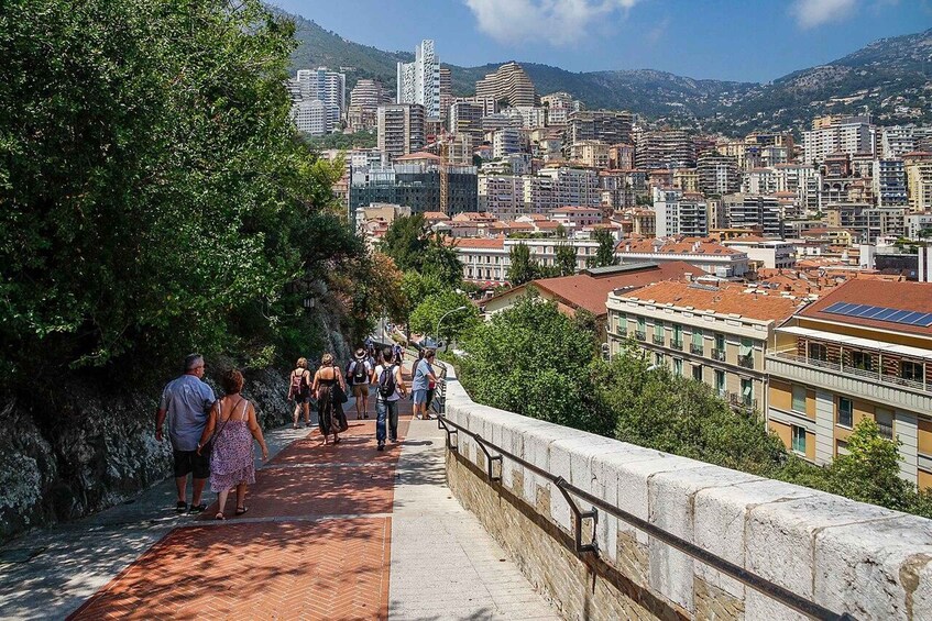 A cityscape with a stone pathway leading to a hilltop, overlooking a densely built urban area with modern and traditional architecture. 2