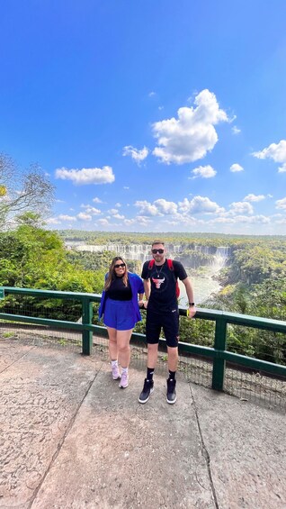 Two people standing on a viewing platform with a waterfall in the background. 2